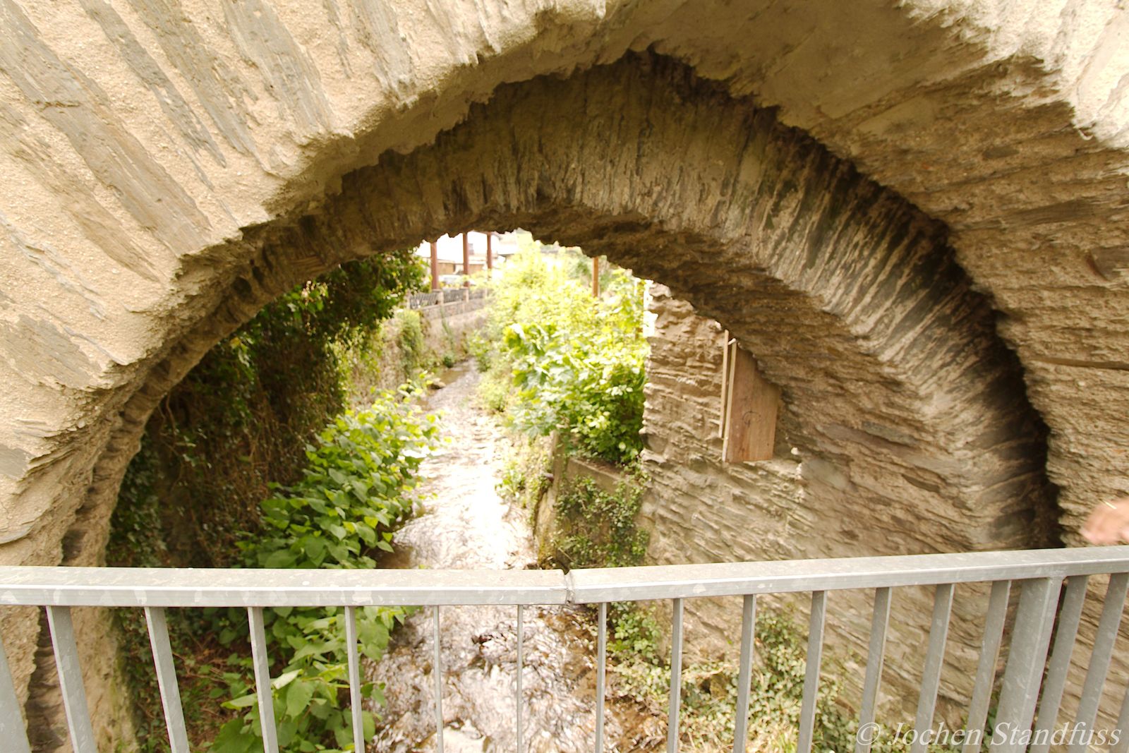 Oberbach fließt durch einen Steinbogen der Stadtmauer in Dausenau